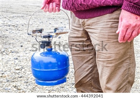 Man holding camping gas portable stove.