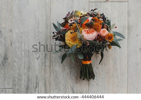 Autumn wedding bouquet made of orange flowers lies on the white wooden table Royalty-Free Stock Photo #444406444