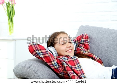 Portrait of young girl with headphones on grey sofa