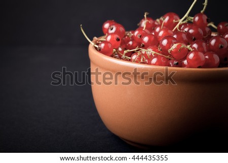 Currant berries in a clay bowl on black background. Selective focus. Shallow depth of field. Toned.