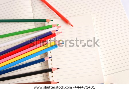 A note book and colorful pencils  background.