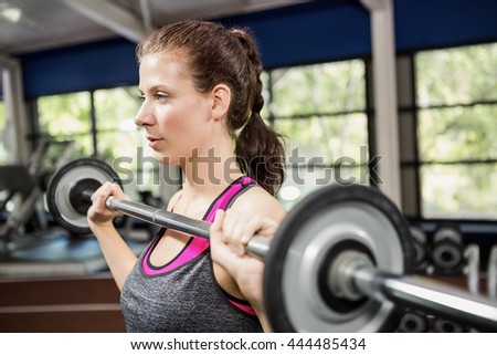Close-up of woman working out with barbell at gym