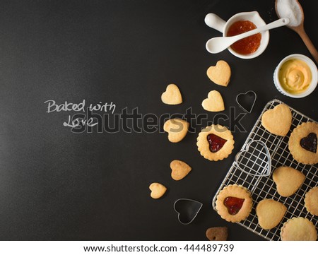 Black bakery text space images with text "Baked with Love" and heart shape cookies cooling on tray. Overhead view text space image.