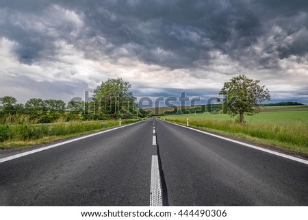 road leading in the middle of the picture with heavy clouds in the sky