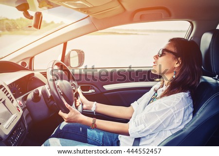 Asian woman driving a car in a happy mood.