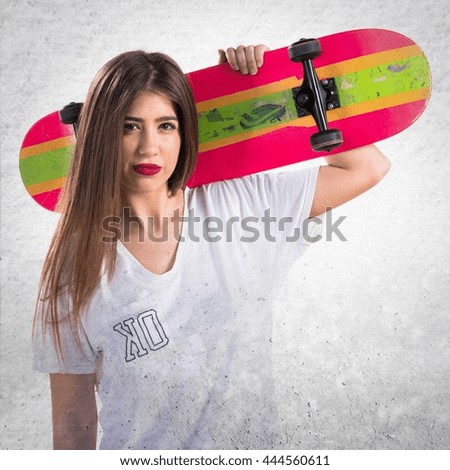 Teen girl holding a skate over grey background