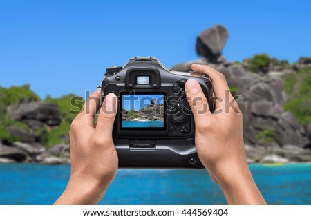 Hands holding the camera which taking photo of Similan islands, Beautiful view of the rock Sail, Thailand