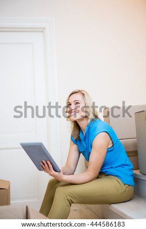 Smiling young woman using digital tablet in new house