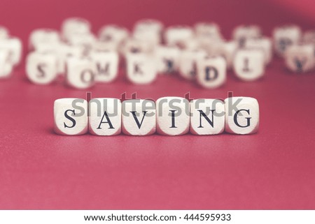 Saving word written on wood cube with red background