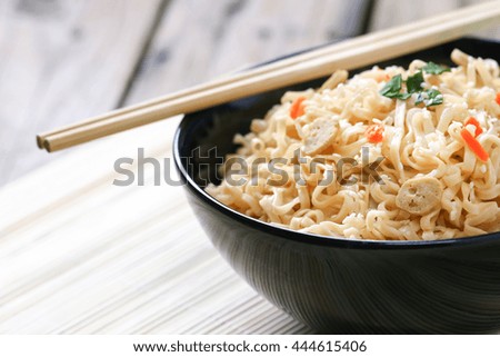 Instant noodles, fried pork, and vegetables on wooden background