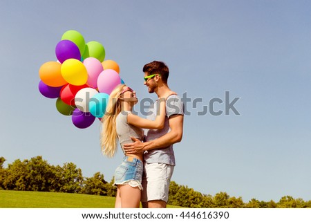 Young happy man huging his girl and holding balloons