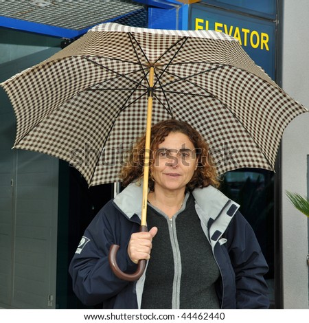 Latin business woman leaving work on a rainy day with her umbrella