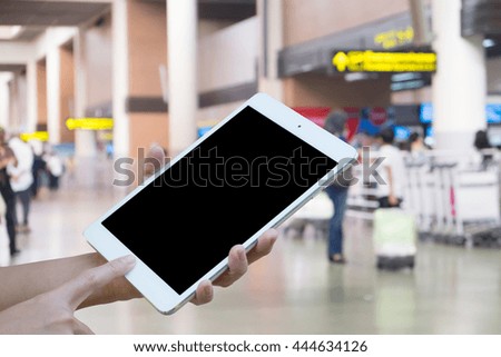 Hands woman are holding touch screen smart phone,tablet on Blurred Traveler at airport terminal for background.
