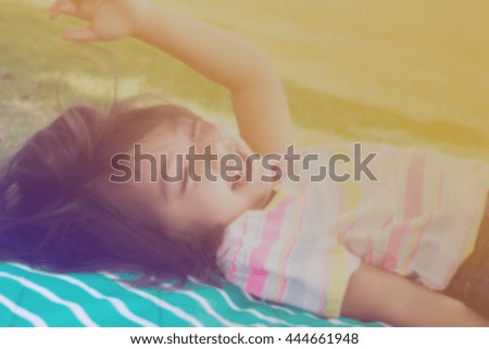 Blurry picture of laughing cute little girl on pad and lawn background, filtered color tone