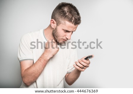 successful man with his fist looking at cell phone, isolated on a gray background