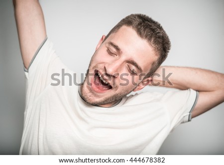 handsome man stretching after sleep, isolated on a gray background