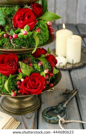 Etagere with flowers and plants. Floral decoration with red roses, mistletoe and moss. 
