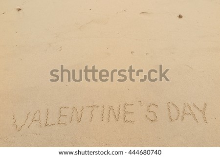 written words "VALENTINE'S DAY" on sand of beach