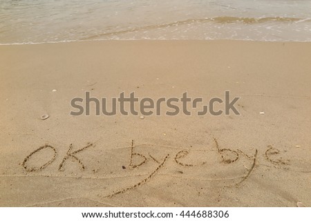 written words "OK bye bye" on sand of beach