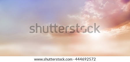 Dreamy Romantic Sky scape - beautiful wide peach and dusky pale blue sky and cloud scape with a burst of sunlight emerging from under the cloud base with plenty of copy space Royalty-Free Stock Photo #444692572