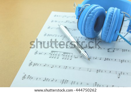 Create or compose this music note paper by myself.pen and blue headphone on sheets music note background.