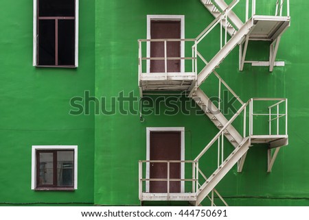 Safety entrance door, exterior staircase on green wall of a building. 