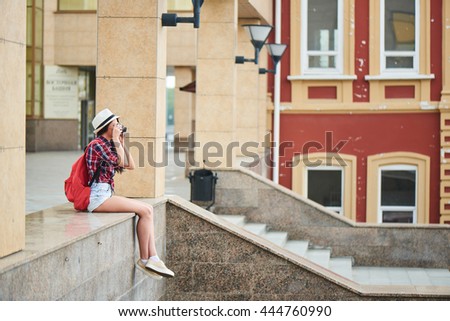 Girl tourist taking pictures of the urban landscape, sitting on a marble surface 