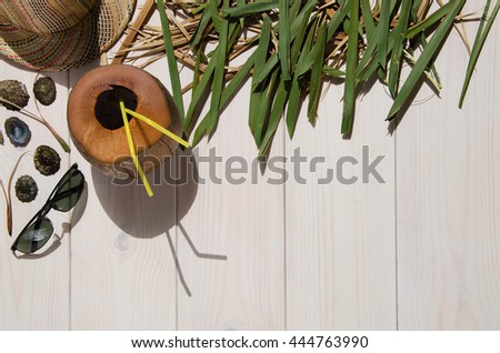 Tropical palm leaf, havana hat, sun glasses and shells on white wooden background with copy space. Concept for vacation or summer.