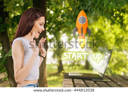 Beautiful young woman sitting in the park, using a laptop, fun start up concept