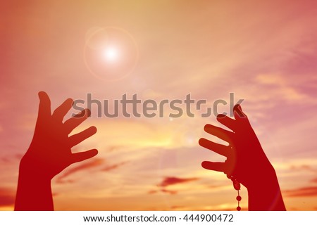 Silhouette hand girl praying at sunset