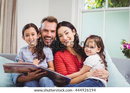Portrait of happy family with picture book sitting on sofa at home