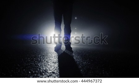 silhouette of feet walking on street at dark night. light and shadow. crime scene of one suspicious person. spooky scary horror fantasy background