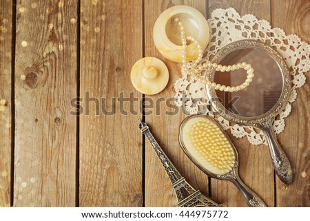 Vintage hand mirror and hairbrush with Eiffel Tower on wooden background. Top view.