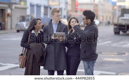diverse multi ethic group of young people talking together standing on city street looking at tablet computer. happiness lifestyle background. teamwork passion spirit scene