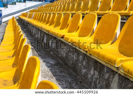 Blank old plastic chairs in an old small stadium. Old worn scratched plastic chairs for the spectators in the stands of the stadium