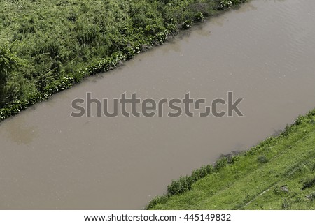 Dark water of the river. Water crossing a green field.