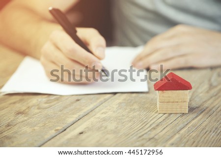 business concepts. Man hand pen and house on wooden table