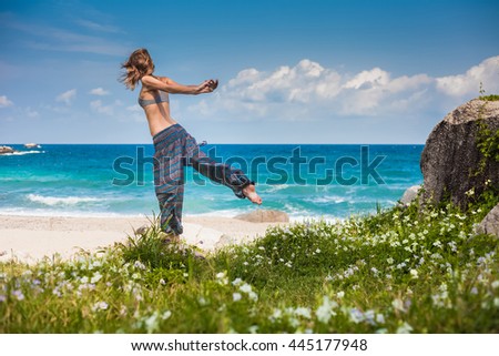 Lady stretching on the sandy beach near blue ocean