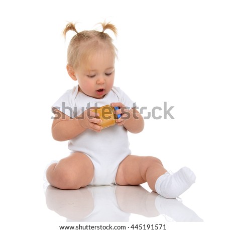 Infant Baby girl kid sitting and holding in hands jar of child mash puree food isolated on a white background
