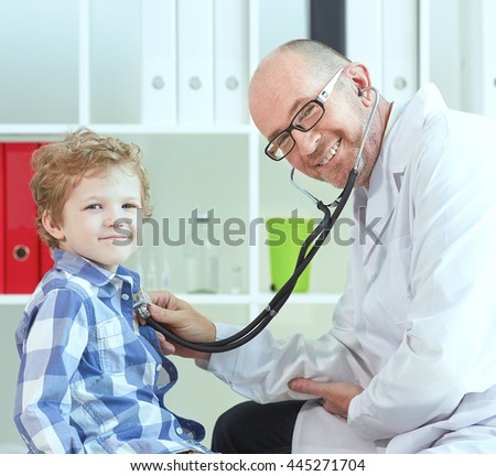Old male doctor examining a child patient by  stethoscope. Health care concept.