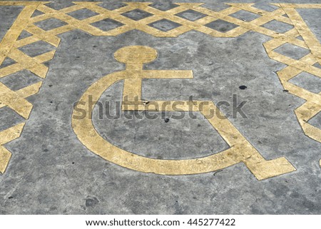 Yellow wheelchair Handicap Sign on dark asphalt and concrete road street background.