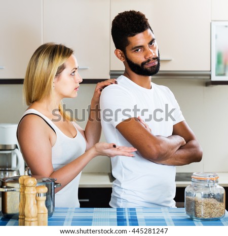 Reconciliation between interracial couple after bad fight in kitchen. Focus on man
