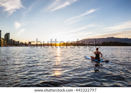 Paddle Boarding around Coal Harbour in Downtown Vancouver during a beautiful cloudy sunset.
