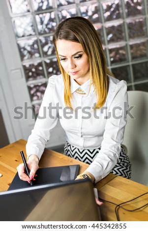 Female designer in office working with digital graphic tablet and laptop. Photography retoucher sitting at desk. Creative people or advertising business concept