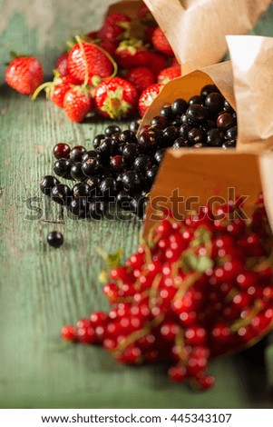 berries (strawberry, mulberry, currant) wrapped in paper on a green wooden table