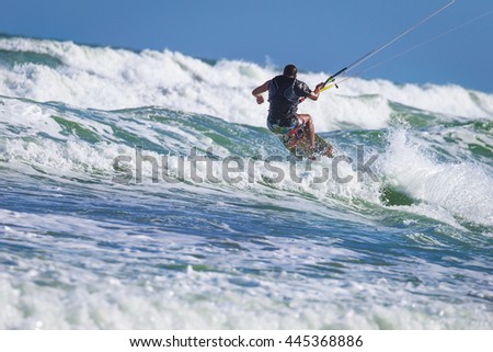 Athletic man riding on kite surf board on a sea waves