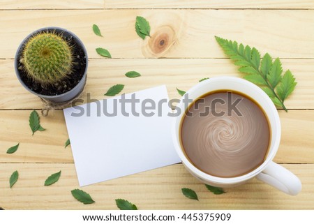 Coffee mug with green foot fern, Flower petals, Cactus flower and notes on yellow rustic table.