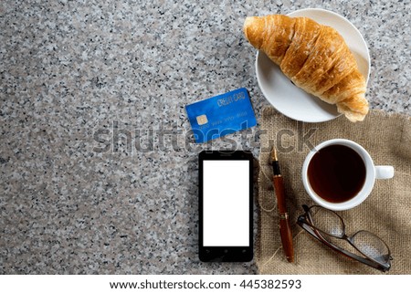 business work on marble table coffee with croissant bakery  top view white space in smartphone 