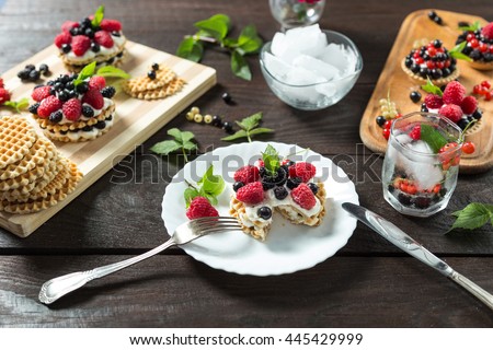 Delicious eaten berry cake on a white plate. Served with lemonade, ice, mint, berry and flowers on wooden table. Silver knife and fork. Horizontal image. 