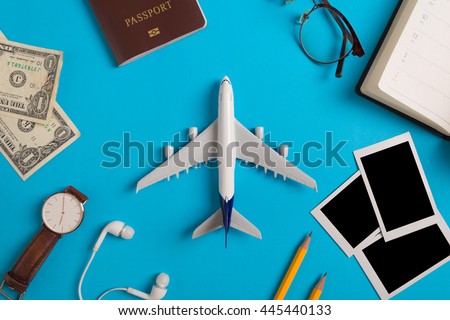 Preparation for Traveling concept, watch, airplane, money, passport, pencils, book, earphone, Photo frame, eyeglass  on blue background with copy space.